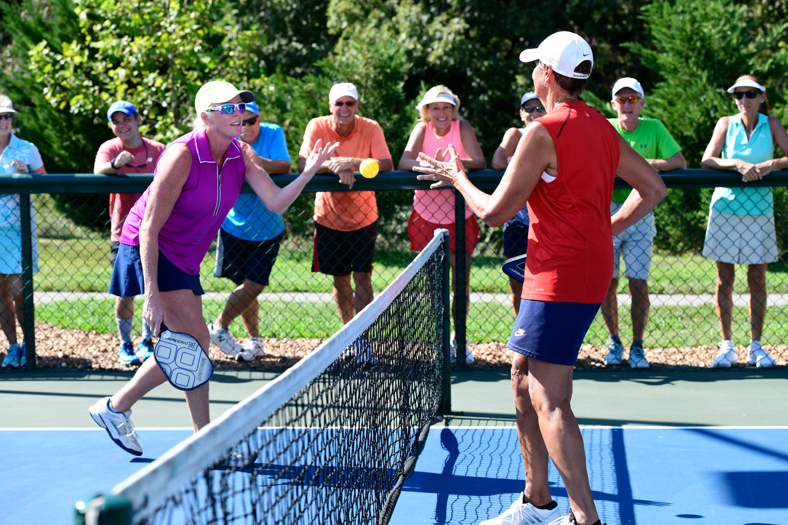 Spectators watching their fellow members of the pickleball club play a game.